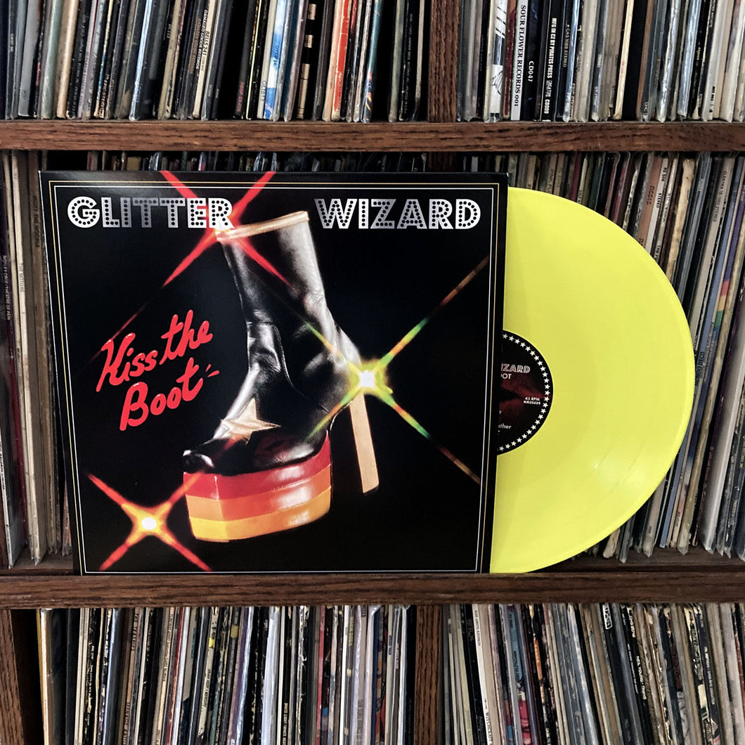 Vinyl record with 'Glitter Wizard' and 'Kiss the Boot' on a shelf of records