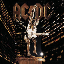 Cargar imagen en el visor de la galería, Statue of a person playing guitar with 'AC/DC' logo above, against a cityscape background.