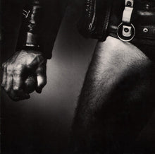 Cargar imagen en el visor de la galería, Black and white close-up of a person's arm and hand wearing a leather jacket.