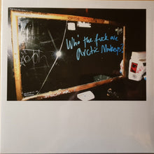 Cargar imagen en el visor de la galería, A vinyl record cover with the title 'Who the Fuck are Arctic Monkeys?' written in marker on a chalkboard. The background shows a dimly lit room with various items.
