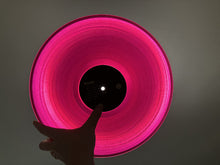 Load image into Gallery viewer, Pink vinyl record held by a hand against a dark background