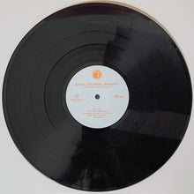 Load image into Gallery viewer, A black vinyl record with a white center label featuring orange text and logo, photographed from above against a plain light background.