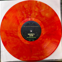Load image into Gallery viewer, A translucent orange-red vinyl record with marbled color variation, featuring a black center label with the text 'BROWN ACID' and 'The Fiftieth Trip'.