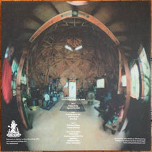 Cargar imagen en el visor de la galería, Wooden interior of a dome-shaped building with text and logos on the back