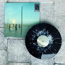 Charger l'image dans la galerie, Vinyl record with a black and white splatter design on a concrete surface, next to its cover.