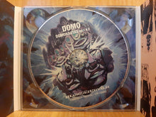 Charger l'image dans la galerie, CD with 'DOMO DOMINANTES Vol. 1 &amp; 2' on a reflective surface