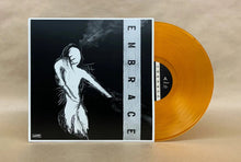 Load image into Gallery viewer, Vinyl record with orange disc and black and white cover featuring the word 'Embrace'.