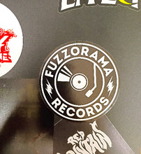Cargar imagen en el visor de la galería, Sticker with 'Fuzzorama Records' design on a reflective surface