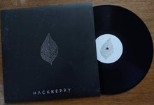Cargar imagen en el visor de la galería, Vinyl record and cover with 'Hackberry' branding on a wooden surface