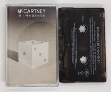 Charger l'image dans la galerie, The image presents a minimalist design for the cassette cover of "McCartney III Imagined." It features a shadowed silhouette of a white dice against a darker background, with the McCartney III album title in a simple, elegant font at the top.