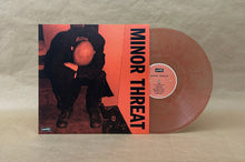 Load image into Gallery viewer, A vinyl record partially pulled from its sleeve, showing a translucent pink record and the album cover for Minor Threat's 'Severed Symmetry'.