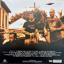 Cargar imagen en el visor de la galería, Album cover with three men standing by a fence, featuring text and a cross in the background.