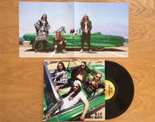 Load image into Gallery viewer, Vinyl record with a green car and people on the cover, placed on a wooden surface.