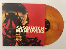 Load image into Gallery viewer, Record cover with a image of a person in a spacesuit against a red background, with the band name 'Sasquatch' and album name 'Maneuvers' in white text.