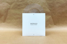 Cargar imagen en el visor de la galería, Clear vinyl record with a white cover on a textured beige background