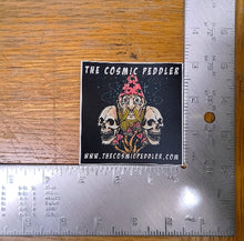 Load image into Gallery viewer, Sticker of 'The Cosmic Peddler' with a ruler for scale on a wooden surface