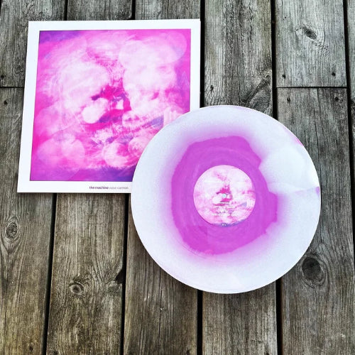 Pink and white abstract art print and disc on a wooden surface