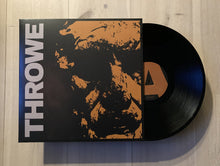 Cargar imagen en el visor de la galería, Vinyl record with cover featuring the name &#39;Throwe&#39; on a wooden surface