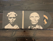 Load image into Gallery viewer, Vinyl record with cover featuring two portraits on a wooden surface