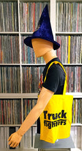 Charger l'image dans la galerie, Mannequin wearing a yellow 'Truckfighters' bag with a blue witch hat in front of a bookshelf.
