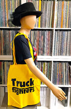 Charger l'image dans la galerie, Mannequin wearing a yellow apron with 'Truckfighters' text in front of a record album collection.