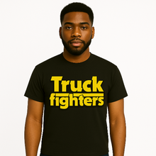 Cargar imagen en el visor de la galería, Man wearing a black t-shirt with &#39;Truck fighters&#39; in yellow text on a white background
