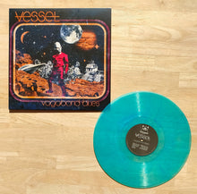 Cargar imagen en el visor de la galería, Vinyl record with a colorful cover featuring a person on an alien planet, on a wooden surface.