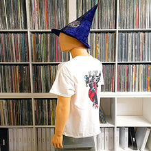 Load image into Gallery viewer, Mannequin wearing a white t-shirt with a graphic design in front of a bookshelf filled with CDs.