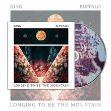 Load image into Gallery viewer, Album cover art for King Buffalo's 'Longing to Be the Mountain,' featuring a centered celestial sun above a symmetrical, abstract mountain landscape in red and white. A physical CD with matching purple and white cosmic artwork is shown partially extracted from the right side.