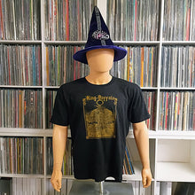 Load image into Gallery viewer, A mannequin wearing a black “King Buffalo” band T-shirt with a gold graphic and a tall purple wizard-style hat, standing in front of shelves filled with vinyl records.