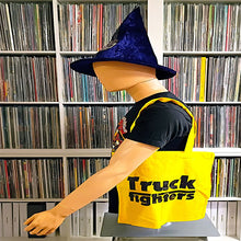 Load image into Gallery viewer, A bright yellow tote bag with black 'Truck fighters' text printed on the front, displayed on a mannequin torso in front of shelves filled with CDs or DVDs.